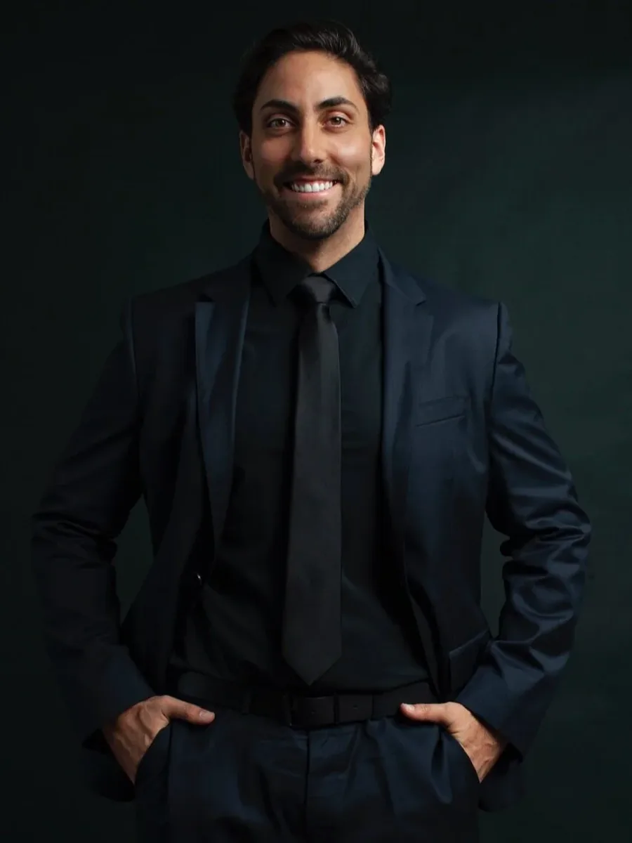 Dominic Labriola, Founding Partner and CEO of Craft & Bauer | Real Broker, standing portrait against a dark green backdrop