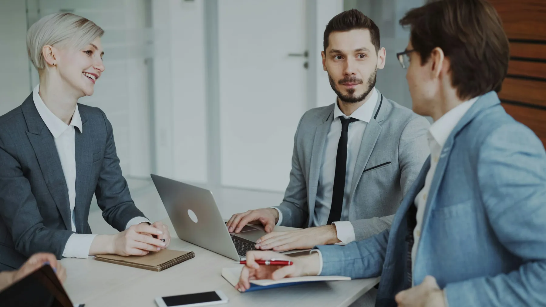 A group of people talking around a table in a meeting room.